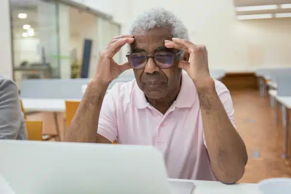 Utilisateur tenant ses munettes devant son écran